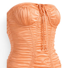 Melato apricot stretch-silk corset dress featuring sculpted underwire cups, directional ruching, and a center-front tie
