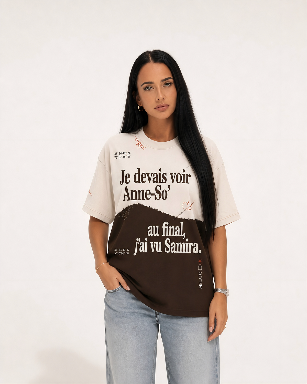 A woman modeling an oversized color-block graphic T-shirt with French text, paired with light-wash jeans, against a plain off-white studio background.